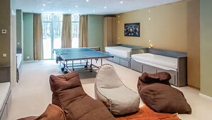 Une pièce avec une table de ping-pong, un canapé, un lit et un tableau au mur.