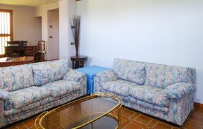 A living room with two patterned sofas, a glass coffee table, and a blue tablecloth.