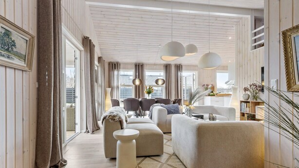 A modern living room with a sofa, armchairs, a coffee table, and pendant lights.