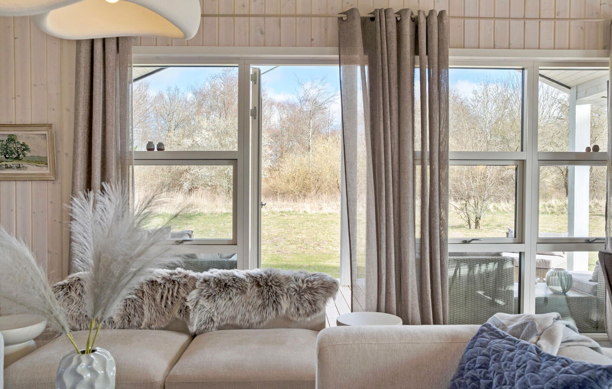 A cozy living room with a large window, a sofa, a coffee table, and a decorative vase.