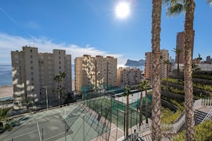 A residential area with high-rise buildings, a tennis court, and a beach in the background.