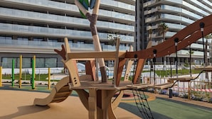A playground with climbing structures and a building in the background.