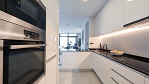 Une cuisine moderne dotée d’appareils électroménagers en acier inoxydable, d’un plan de travail noir et donnant sur l’espace de vie.