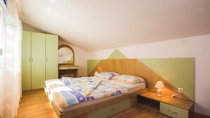 Un dormitorio con cama, mesita de noche, lámpara, armario y espejo.