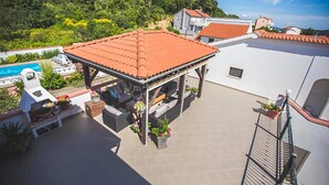 Terraza en la azotea con techo de tejas, mobiliario exterior y piscina.