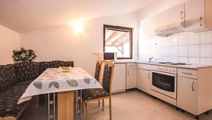 Cocina compacta con comedor, microondas, horno y ventana con vistas.