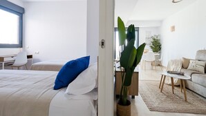 Una habitación de hotel moderna con una cama, un escritorio, una silla, un sofá y una planta en maceta.