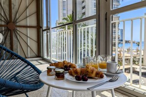 A breakfast setup on a balcony with croissants, cherries, honey, orange juice, and a coffee cup. - MAR BLAU sea view apartment (Benidorm)