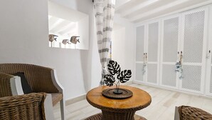 A modern living room with a round wooden table, wicker chairs, a decorative metal plant, and a large window with a white curtain. - POSIDONIO old town apartment (La Vila Joiosa)