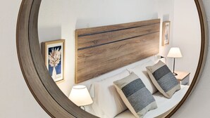 A bedroom with a wooden headboard, two bedside lamps, and a mirror on the wall. - POSIDONIO old town apartment (La Vila Joiosa)
