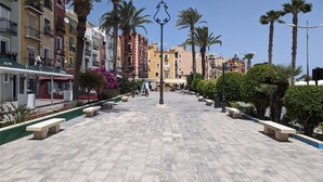 A paved pedestrian area with benches and palm trees, surrounded by colorful buildings. - POSIDONIO old town apartment (La Vila Joiosa)