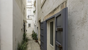 A narrow alleyway with a door on the right and potted plants lining the path. - A Casa di Marilù by Rentbeat (Martina Franca)