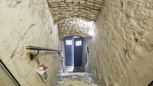 A narrow stone-walled corridor with a marble staircase leading to a door with a blue frame and decorative glass panels. - A Casa di Marilù by Rentbeat (Martina Franca)