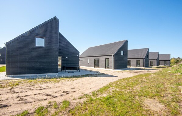 Contemporary buildings with triangular roofs and large windows line a sandy path.