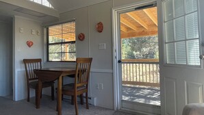 Un comedor con una mesa y sillas de madera, una ventana con persianas y una puerta que da al exterior.
