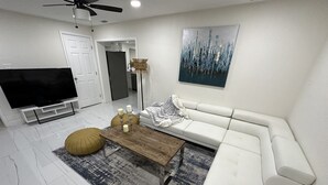 A modern living room with a white sofa, a wooden coffee table, and a large flat-screen TV. - Charming 4-bedroom house for the entire family (sixth court)