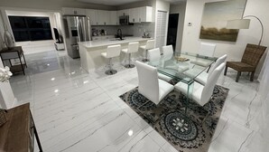 A modern kitchen with white cabinets, stainless steel appliances, and a central island with bar stools. - Charming 4-bedroom house for the entire family (sixth court)