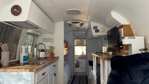 A compact RV kitchen with a wooden countertop, a sink, and a clock.