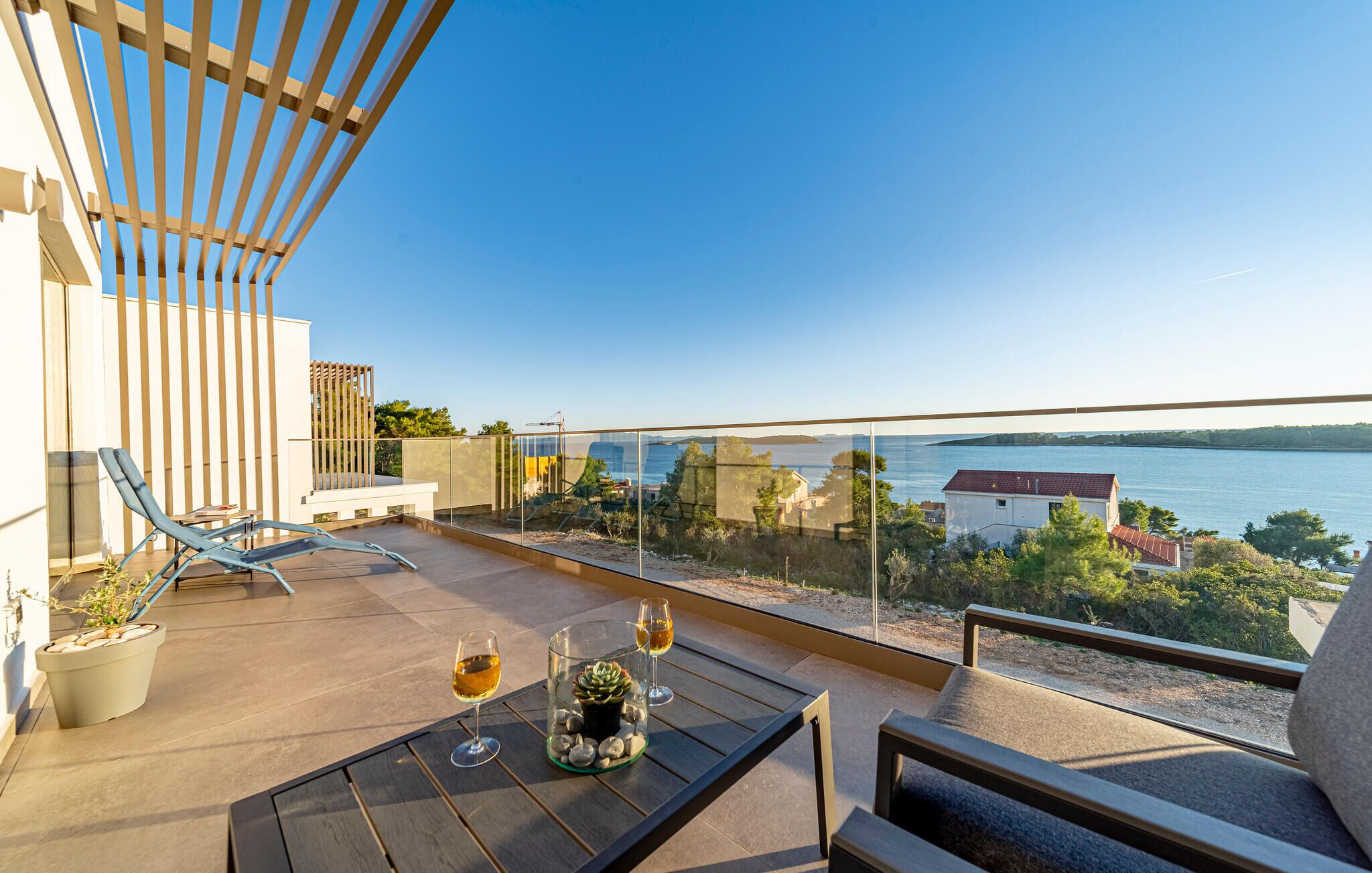 A balcony with a table, two chairs, and two glasses of wine.