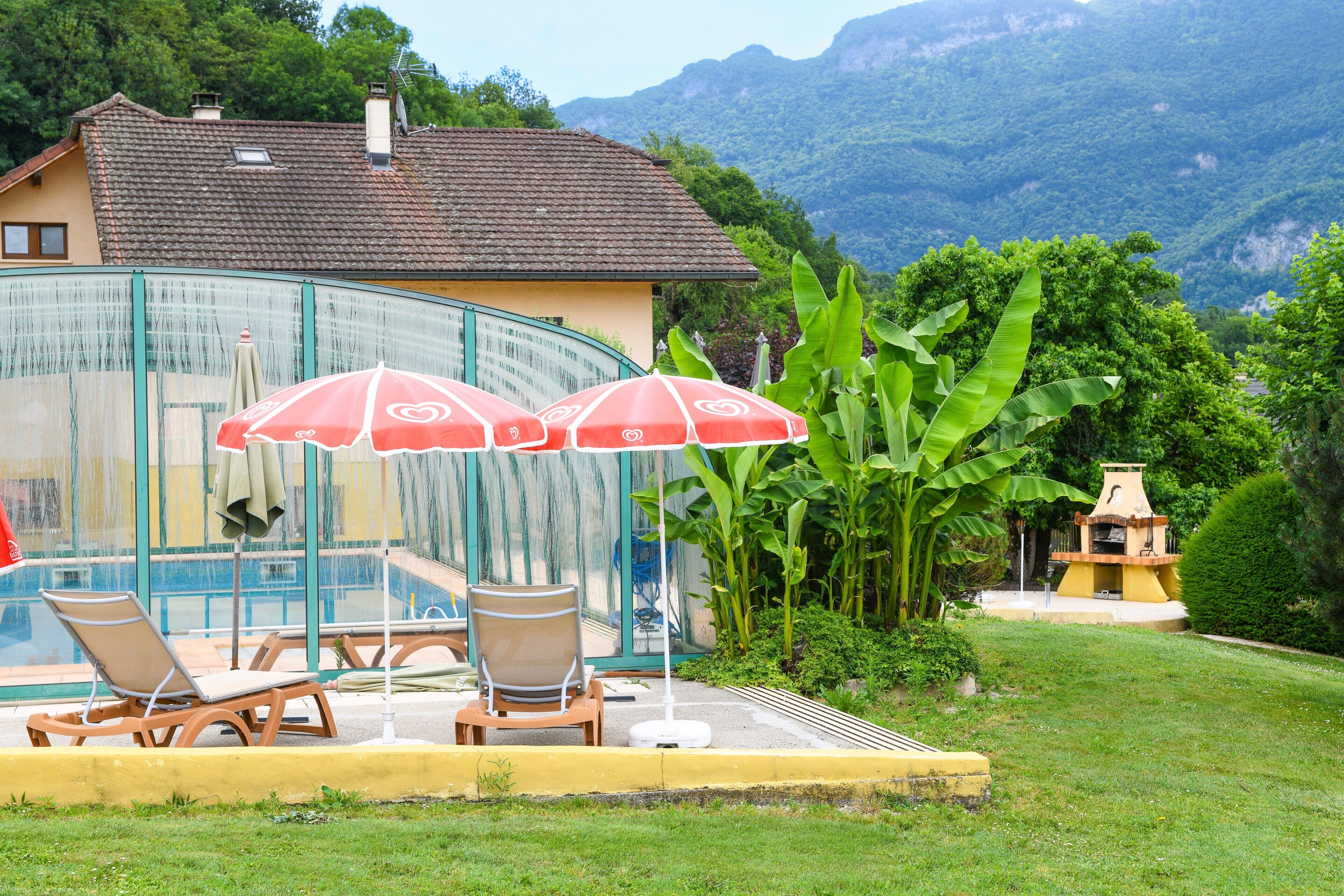 A house with a swimming pool, lounge chairs, and umbrellas.