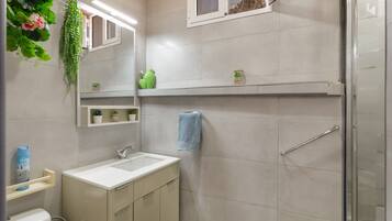 Une salle de bain équipée d’un lavabo, d’un miroir, d’un porte-serviettes et d’un espace douche.