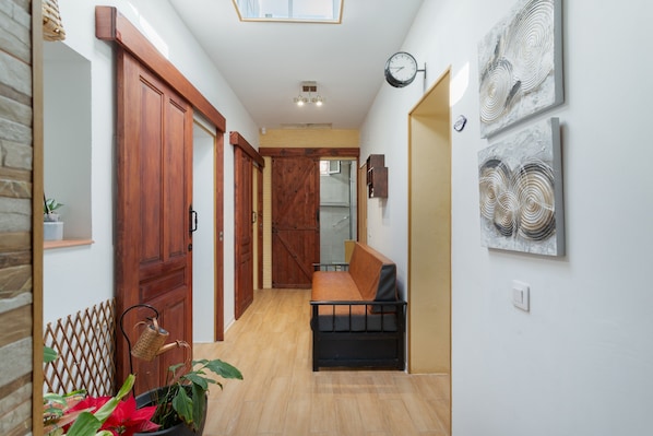A hallway with wooden doors, a bench, and wall art.