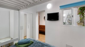 A modern room with a bed, a TV, a desk, and a wardrobe.