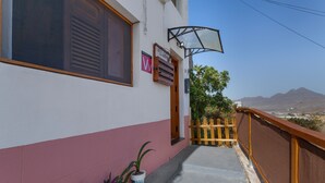 A building with a balcony, a wooden fence, and a view of distant mountains.