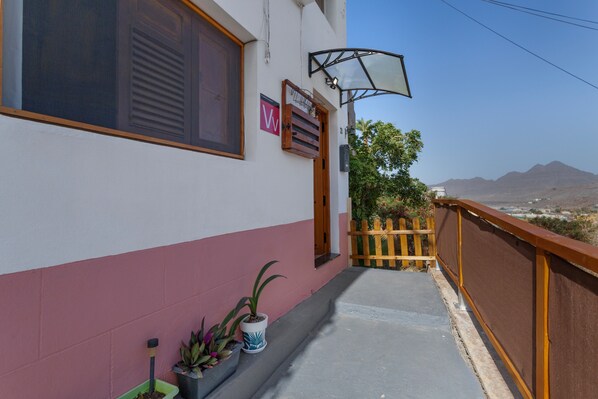 A building with a balcony, a wooden fence, and a view of distant mountains.
