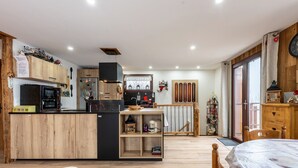 A compact kitchen with a central island, wooden cabinets, and a dining area with a table and chairs. - Holiday Home 'D'Aillon' with Mountain Views, Private Terrace, and Wi-Fi (Aillon-le-Jeune)
