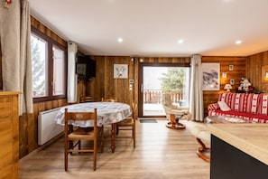 A wooden interior with a dining table, chairs, a sofa, and a view through a glass door. - Holiday Home 'D'Aillon' with Mountain Views, Private Terrace, and Wi-Fi (Aillon-le-Jeune)