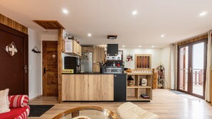 A modern kitchen with wooden cabinets, a central island, and a dining area with a glass table and cushioned seating. - Holiday Home 'D'Aillon' with Mountain Views, Private Terrace, and Wi-Fi (Aillon-le-Jeune)