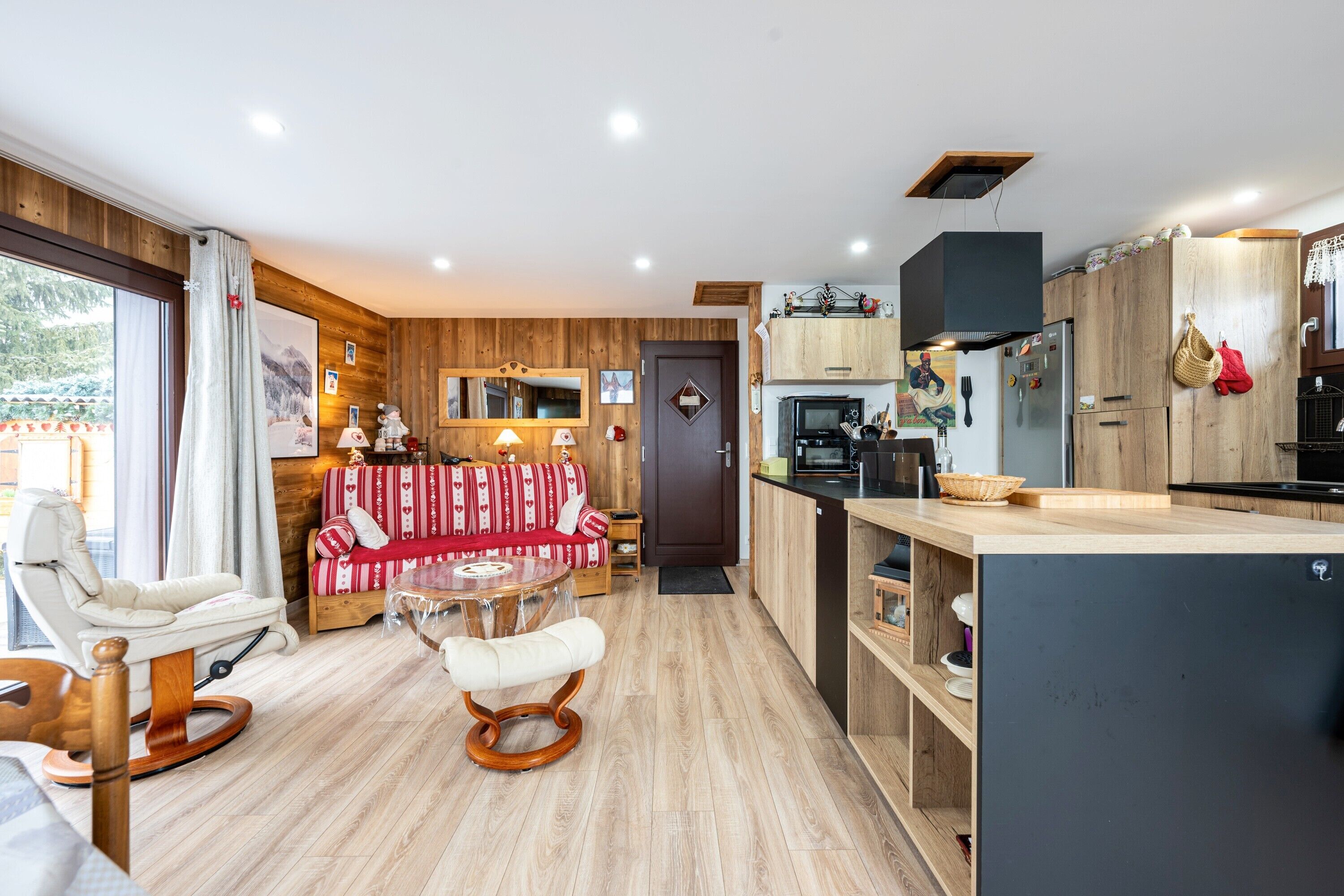 A modern kitchen with wooden cabinets, a dining area with a table and chairs, and a cozy seating area with a sofa.