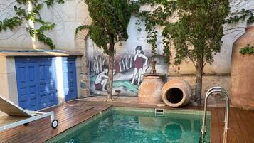 An indoor swimming pool with a wooden deck, a mural on the wall, and a blue door.