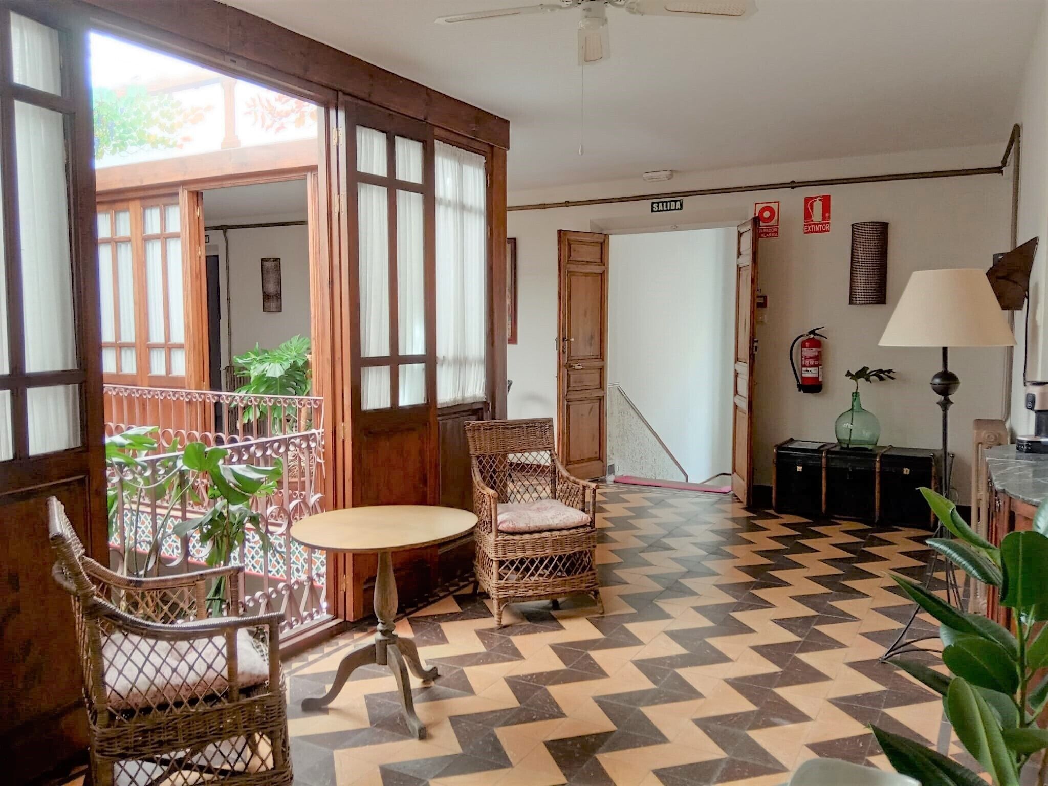 Une pièce avec un sol à motifs, des meubles en osier, une table et une chaise.