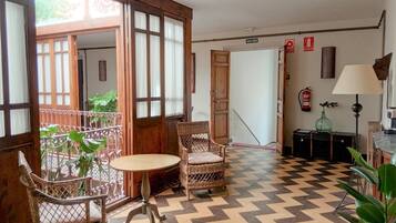 Une pièce avec un sol à motifs, des meubles en osier, une table et une chaise.