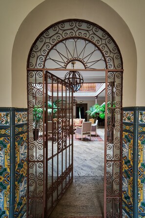 An arched entrance with decorative metalwork, a tiled floor, and a seating area with chairs and a table. - La Falleba Room, Rural Hotel in Consuegra, Toledo (Consuegra)