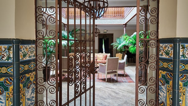 An arched entrance with decorative metalwork, a tiled floor, and a seating area with chairs and a table. - El Pajar Room, Rural Hotel in Consuegra, La Mancha (Consuegra)