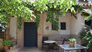 A courtyard with a door, a table, chairs, and potted plants. - El Pajar Room, Rural Hotel in Consuegra, La Mancha (Consuegra)