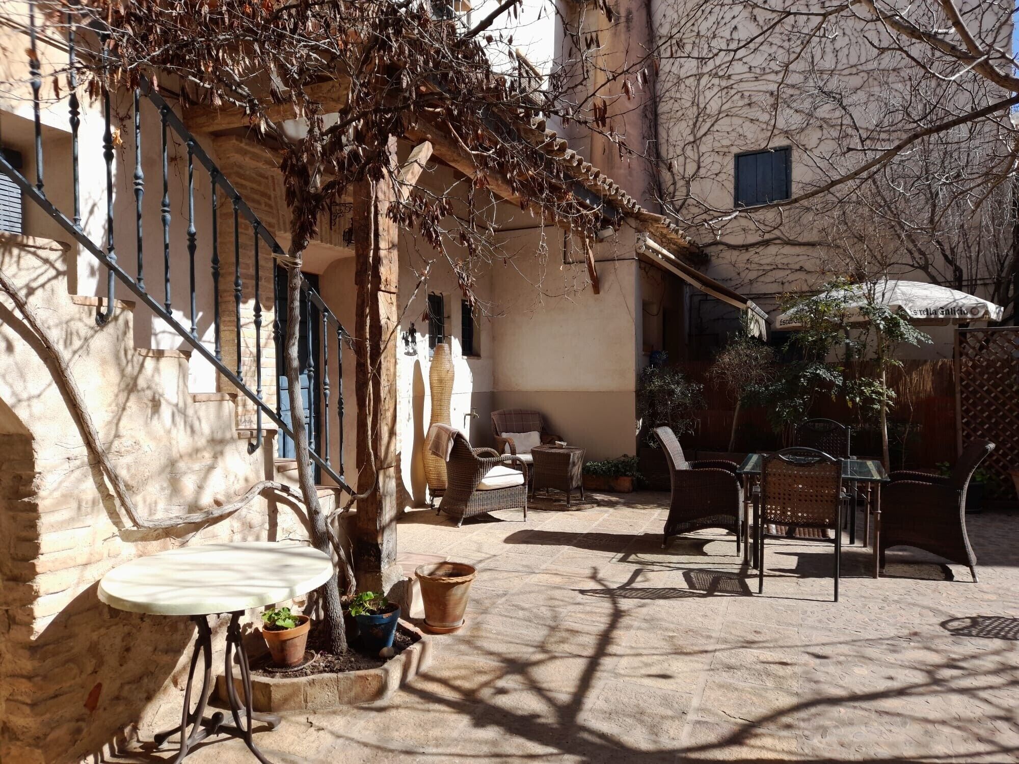 A courtyard with outdoor seating, potted plants, and a staircase.