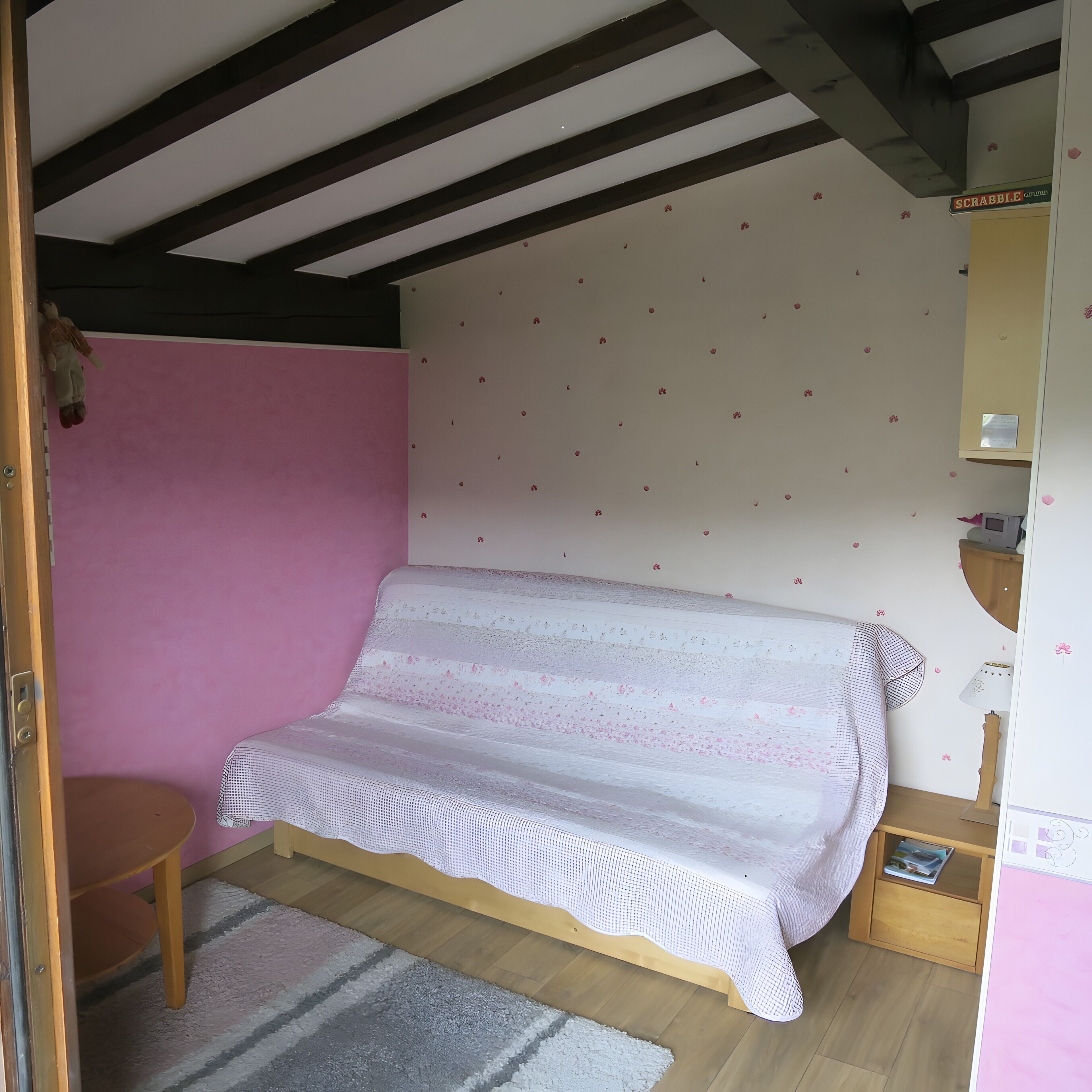 A room with a bed, a small table, a lamp, and a wall with a pattern.