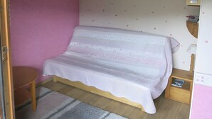A room with a bed, a small table, a lamp, and a wall with a pattern. - Studio Apartment 'Saint-Gervais' with Mountain View, Shared Pool and Private Garden (Saint-Gervais-les-Bains)