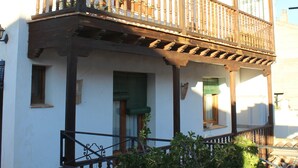 Un bâtiment à deux étages doté d’un balcon, de poutres en bois et de plantes en pot.