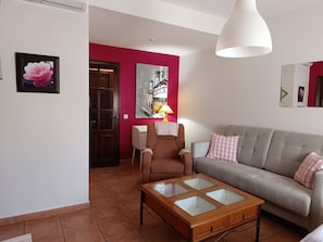 Una sala de estar con sofá, sillón, mesa de centro y obras de arte en las paredes.
