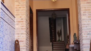 A hallway with a staircase, a wooden chair, and a hanging light fixture. - Apartamento Corredor in Consuegra – Rural Getaway in La Mancha (Consuegra)