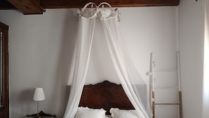 A bedroom with a canopy bed, a wooden headboard, a bedside table with a lamp, and a wooden ladder against the wall. - Apartamento Corredor in Consuegra – Rural Getaway in La Mancha (Consuegra)