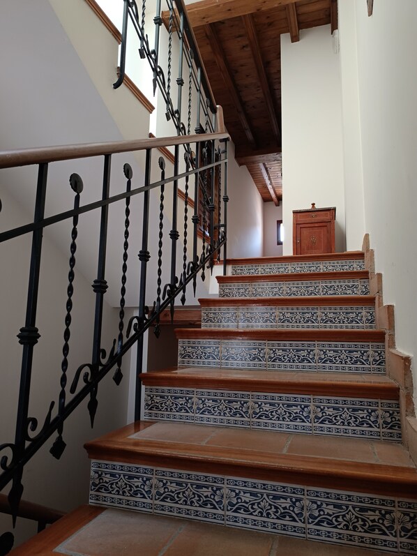 Una escalera con barandillas negras ornamentadas y escalones de baldosas con diseño.