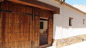 A wooden door with a metal latch, a stone wall, and a small window on a building.