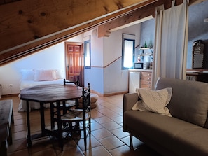 Ett mysigt sovrum på vinden med ett träpanelat tak, en säng, ett litet bord och en soffa.