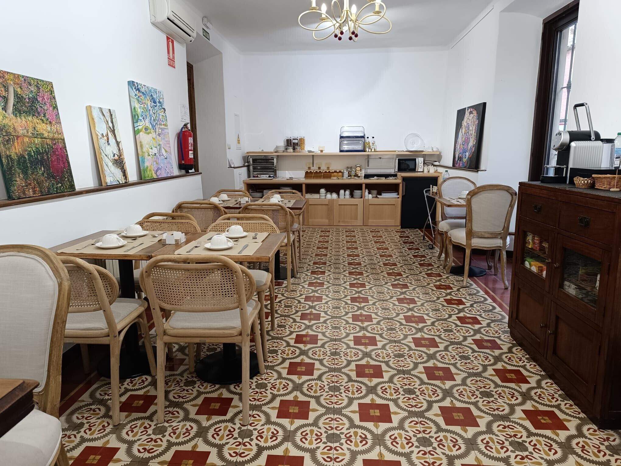 Un comedor con mesas y sillas de madera, piso estampado y obras de arte en las paredes.